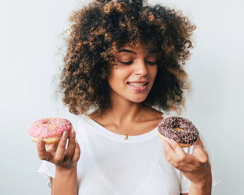 Woman with curly hair looking at two donuts