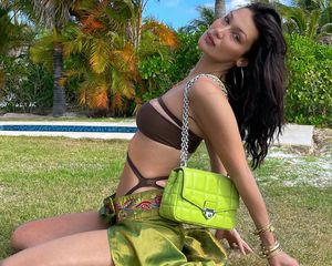 Bella Hadid wears a brown swimsuit, green silk skirt, and lime green purse