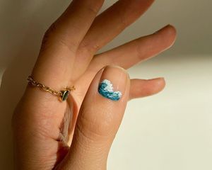 Manicure with neutral base and intricate ocean wave design on thumbnail