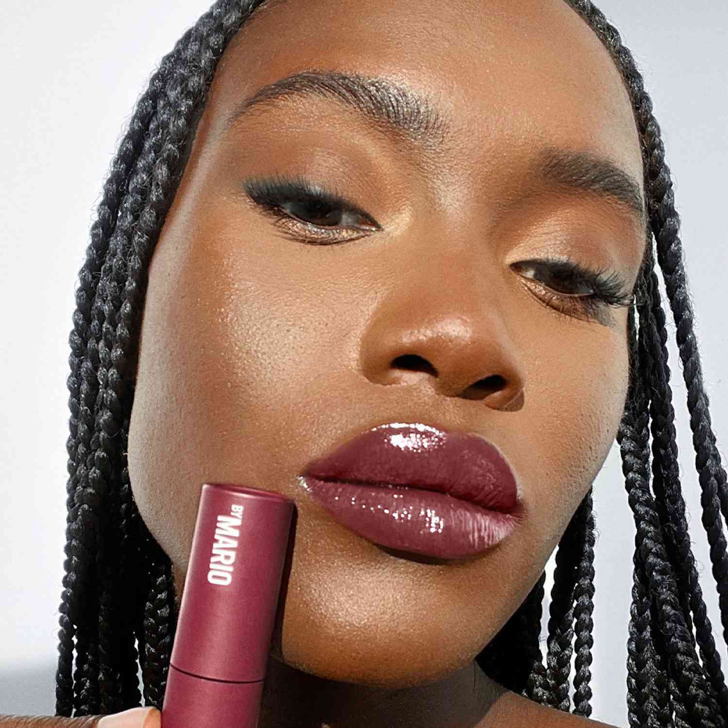 Model with box braids, subtle lashes, and a glossy berry-toned lipstick look