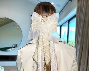 Back view of low ponytail hairstyle with oversized lace and pearl-encrusted bow