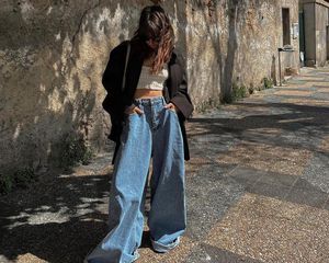 Woman wearing knit crop top, wide leg jeans, and oversized blazer