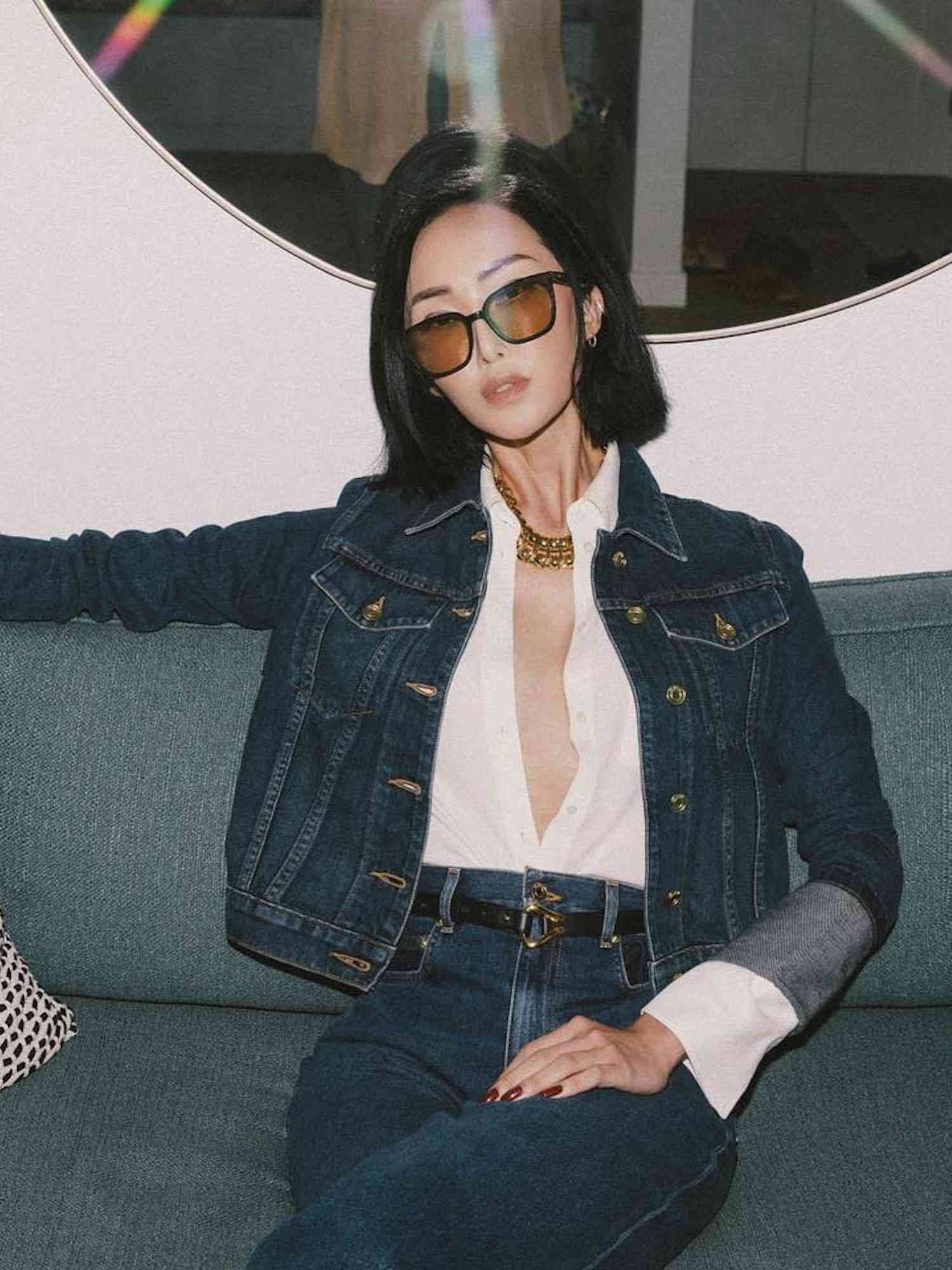 Chriselle Lim wears an unbuttoned white shirt, denim jacket, jeans, and tinted sunglasses