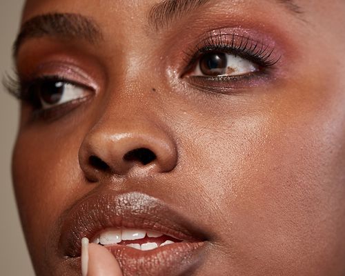 Close-up of woman wearing false lashes, shimmery pink eyeshadow, and shimmery lipstick