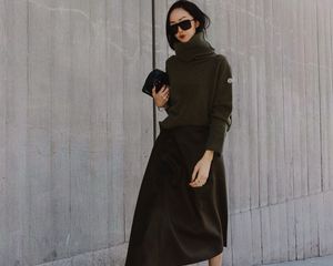 Chriselle Lim wears a turtleneck sweater, slip skirt, clutch handbag, and oversized shield sunglasses