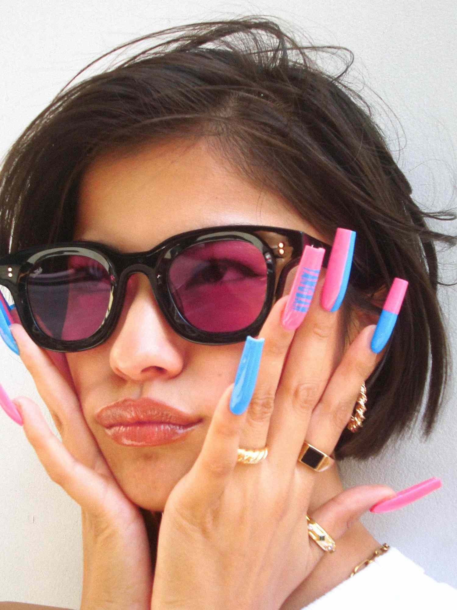 Woman with black and pink sunglasses and pink and blue square-shaped long manicure