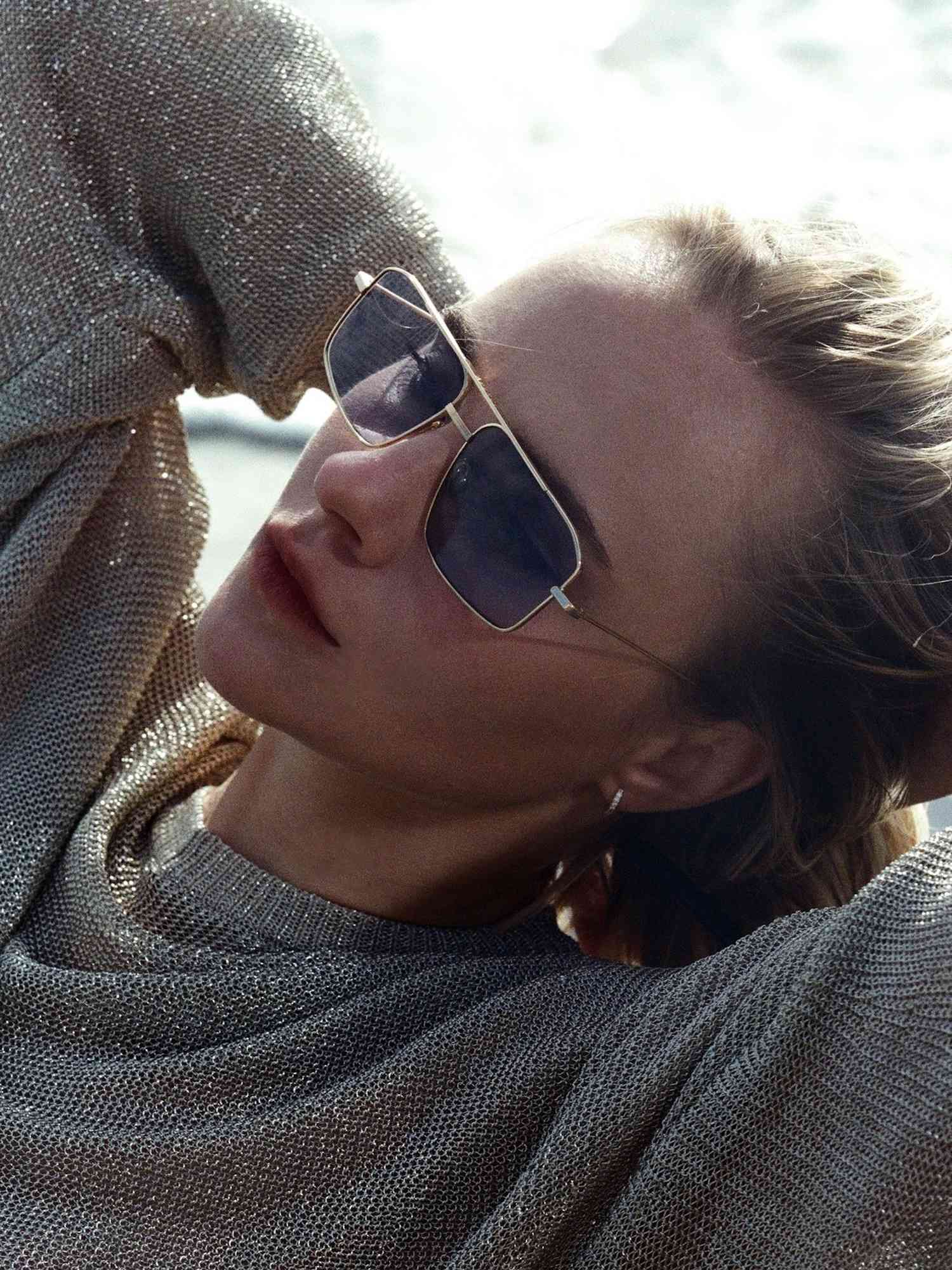 Woman wearing aviator sunglasses with metal frames and blue tinted lenses