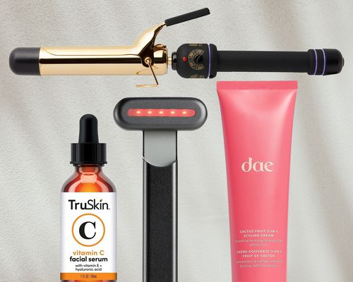  Curling iron, skincare tool, vitamin c serum, and styling cream on gray background