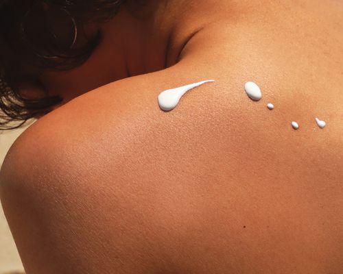 A woman's back with five drops of sunscreen