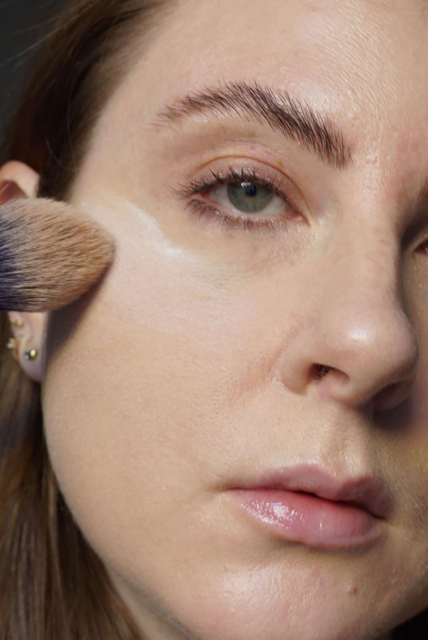 The author adds translucent powder under her eyes with a fluffy brush