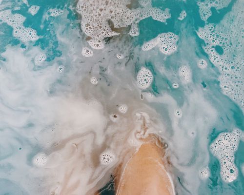 person taking a bath with sudsy water