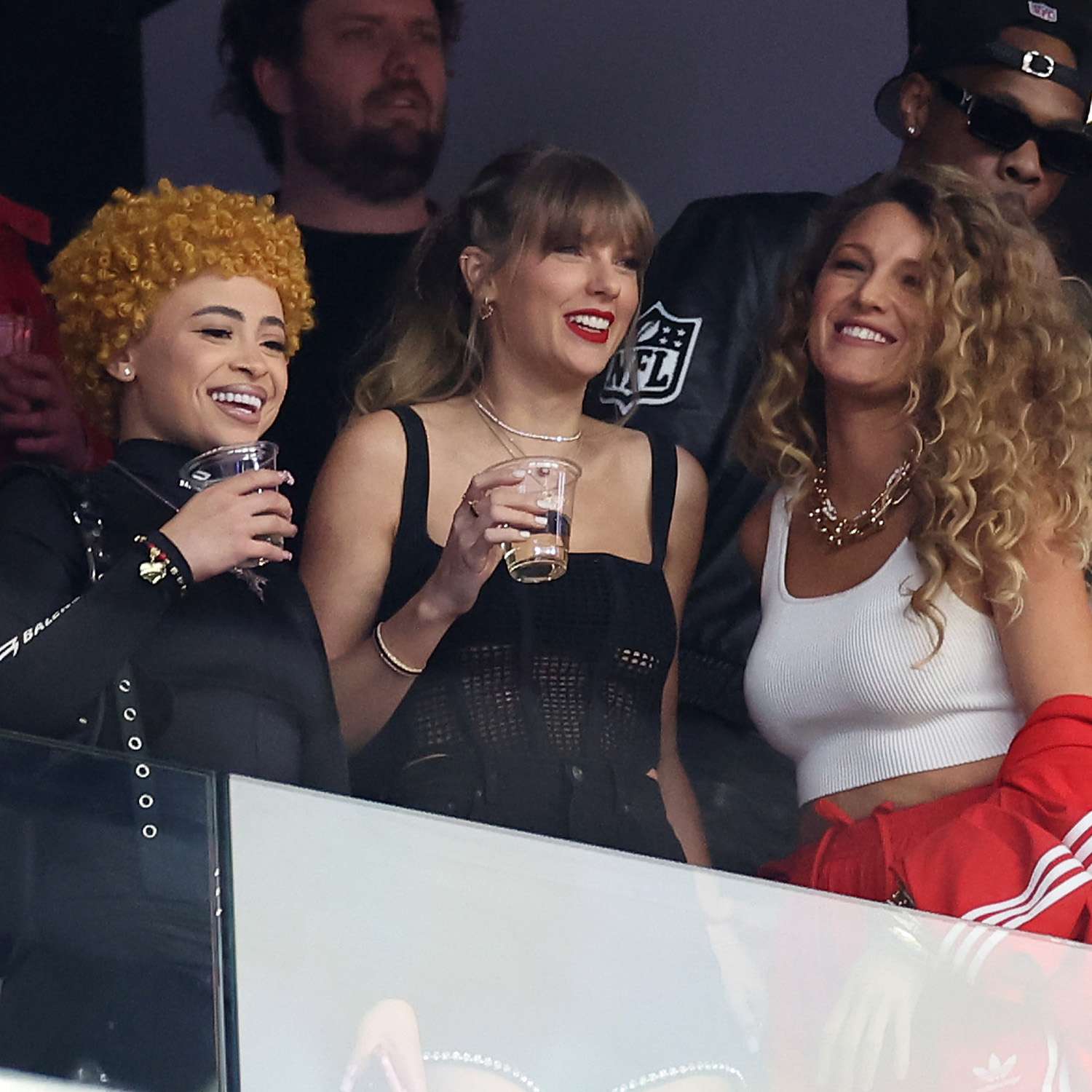 Blake lively standing next to Taylor swift and ice spice at the Super Bowl with big, voluminous curly hair