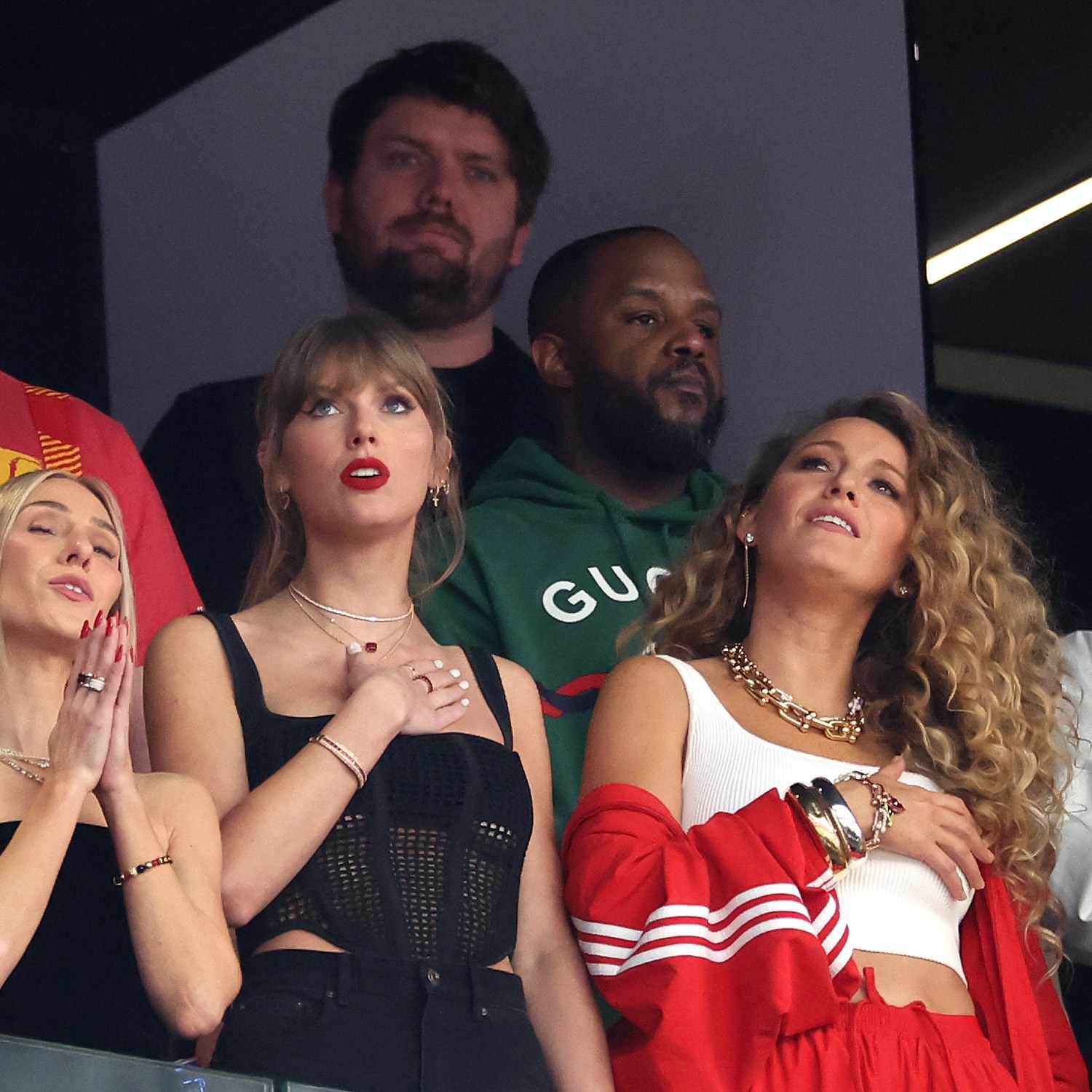 Blake lively standing next to Taylor swift at the Super Bowl with big, voluminous curly hair