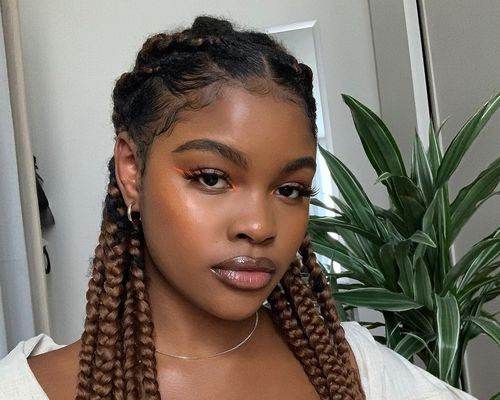 A woman with box braids pulled off her face in a half-up, half-down style