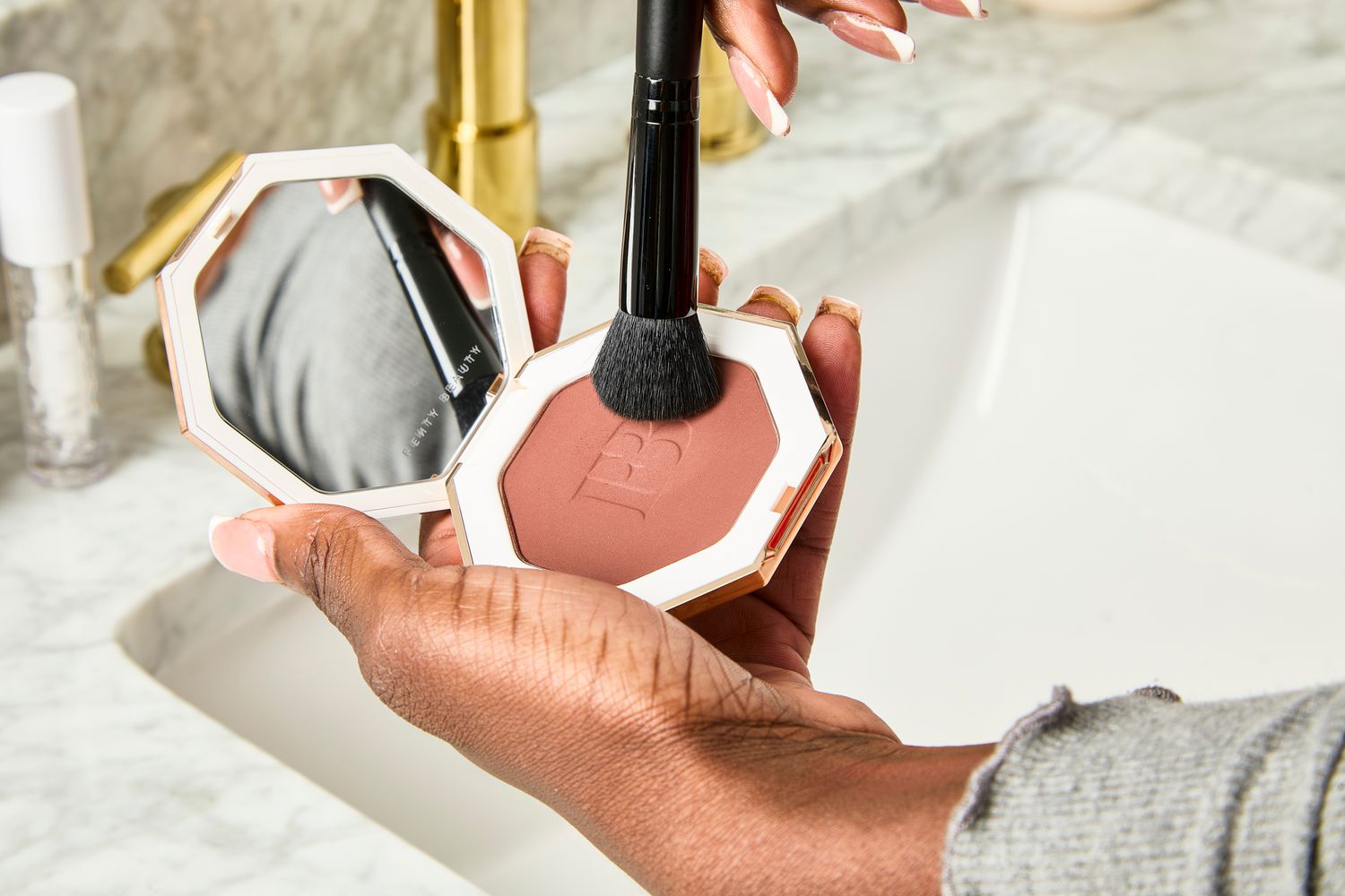 A person uses a makeup brush to apply Fenty Beauty Sun Stalk'r Instant Warmth Bronzer