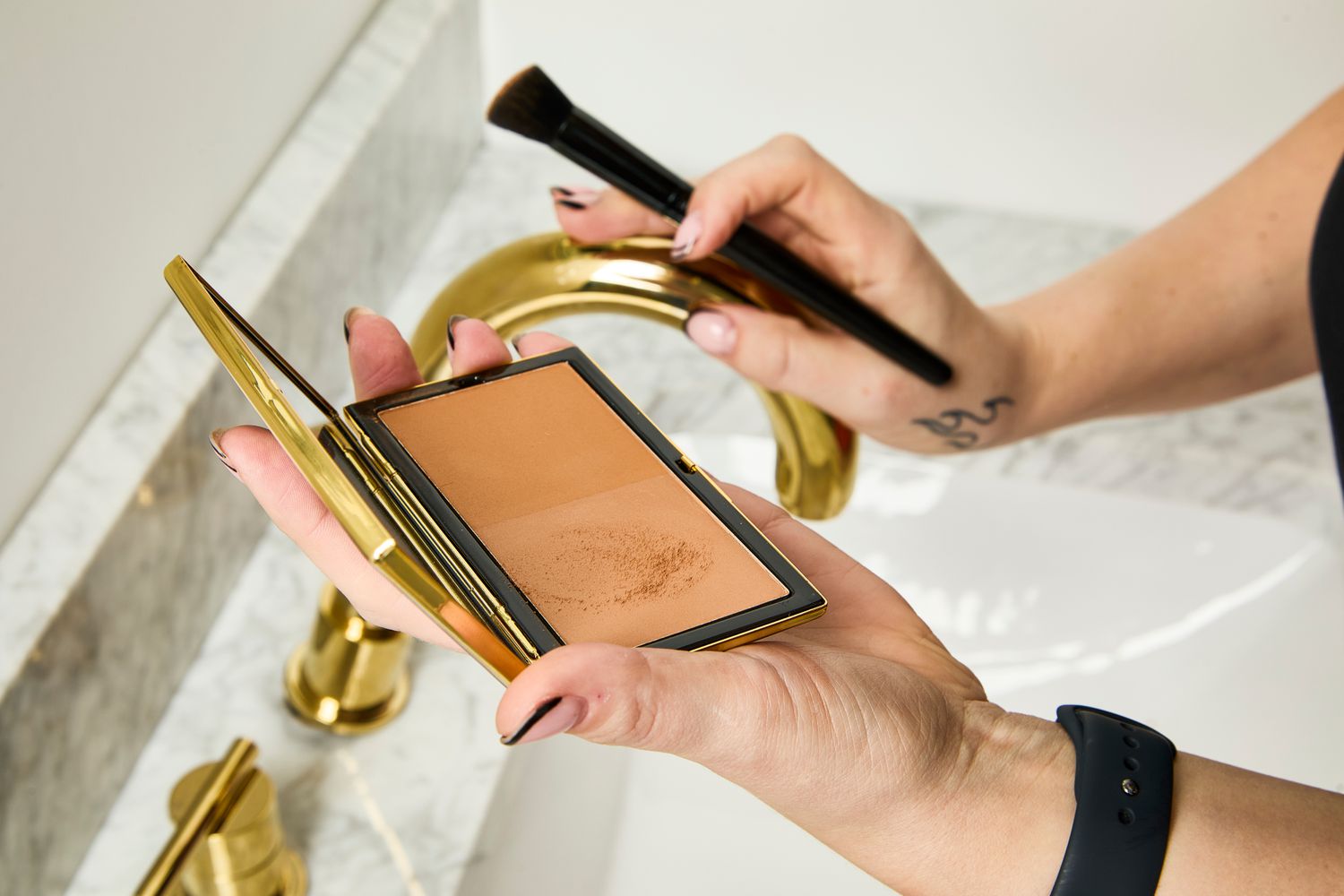 A person applies Victoria Beckham Beauty Matte Bronzing Brick with a makeup brush