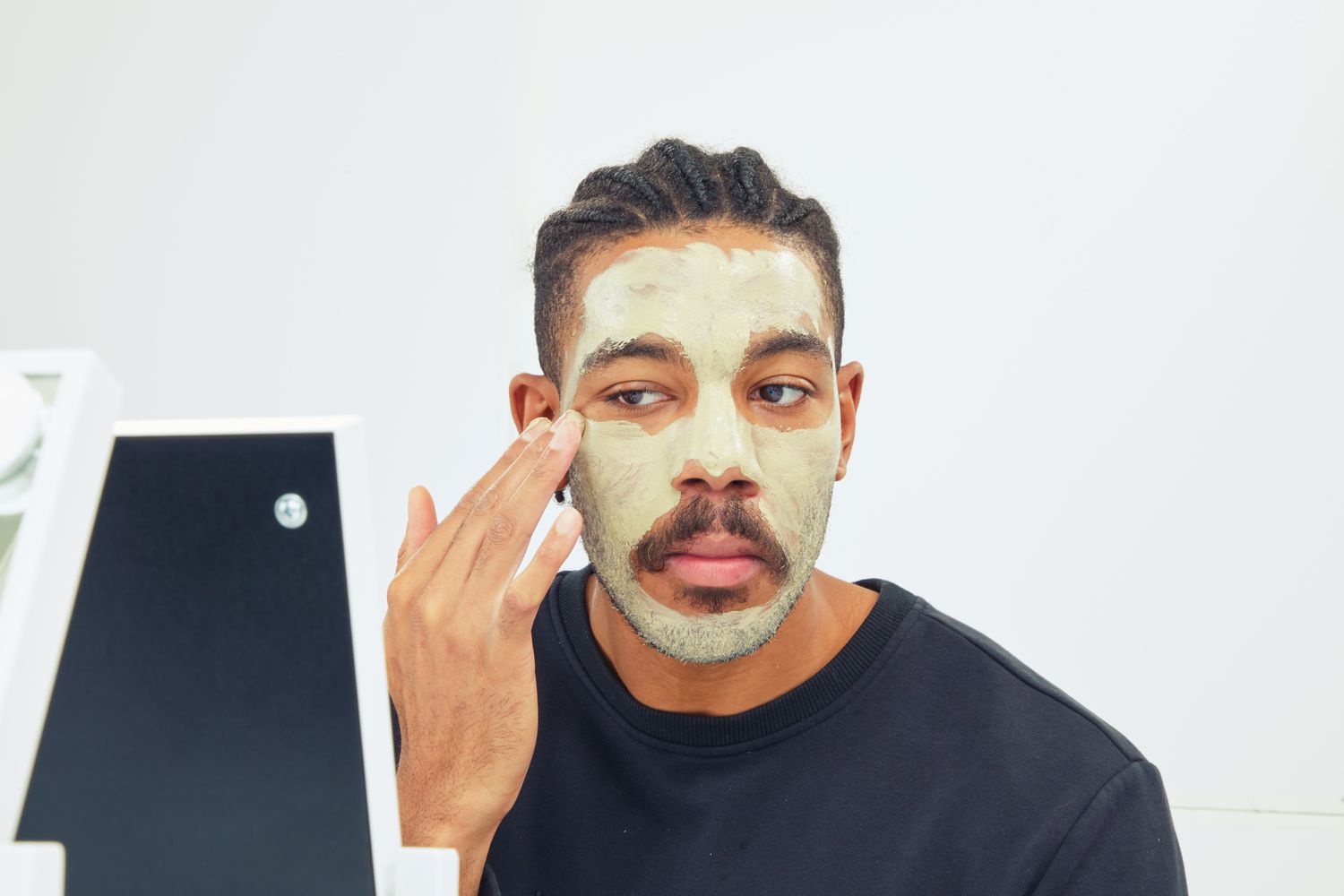 man spreading Fresh Umbrian Clay Purifying Mask on face with fingertips