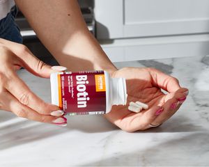 Closeup of a person pouring Jarrow Formulas Biotin pills into their hand on a counter