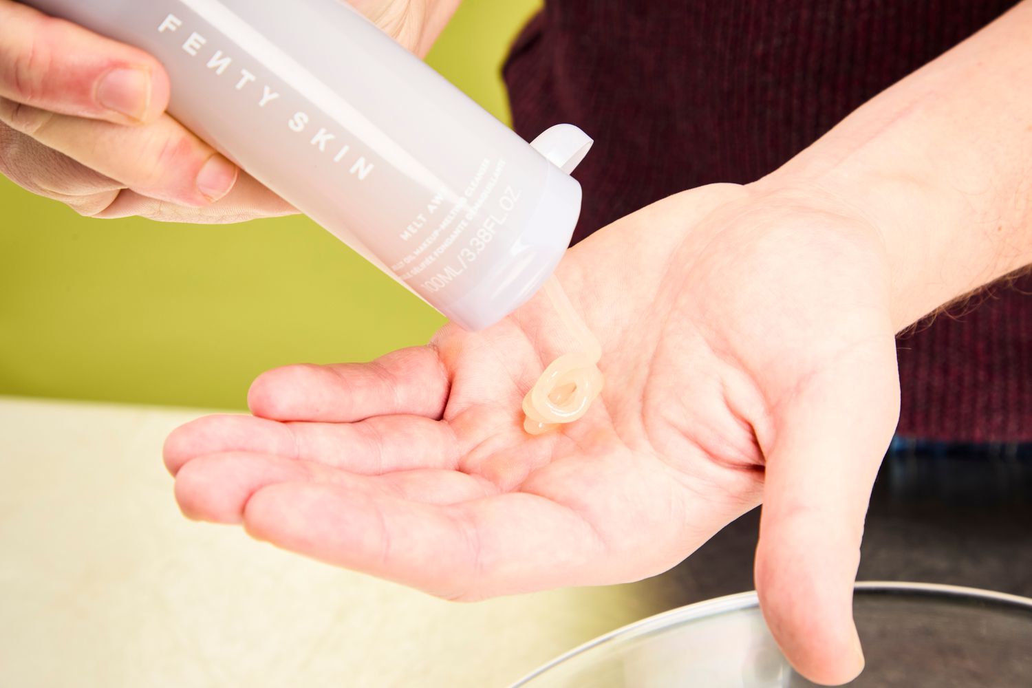 A person dispensing Fenty Skin Melt Awf Jelly Oil Makeup-Melting Cleanser into their hand