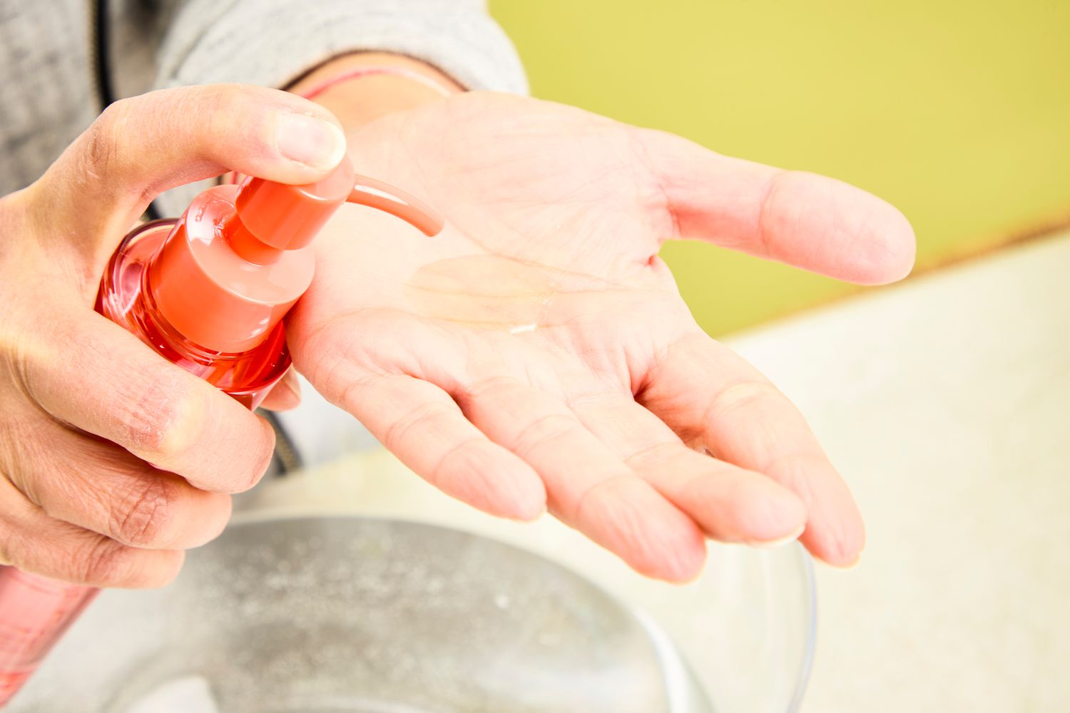 A person dispensing Peach & Lily Ginger Melt Cleansing Oil into their palm