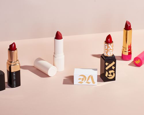 A variety of red lipsticks on a pink background