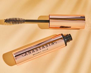 Anastasia Beverly Hills Strong Hold Clear Brow Gel displayed on gold fabric