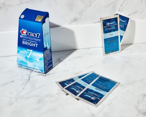 Teeth Whitening with Crest 3D White Strips packets and box on a marble counter