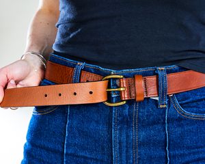 Person wearing blue jeans with Madewell leather belt