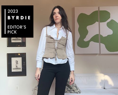 Byrdie editor Madeline Hirsch wears a white button-down, tan corseted top, and black trousers