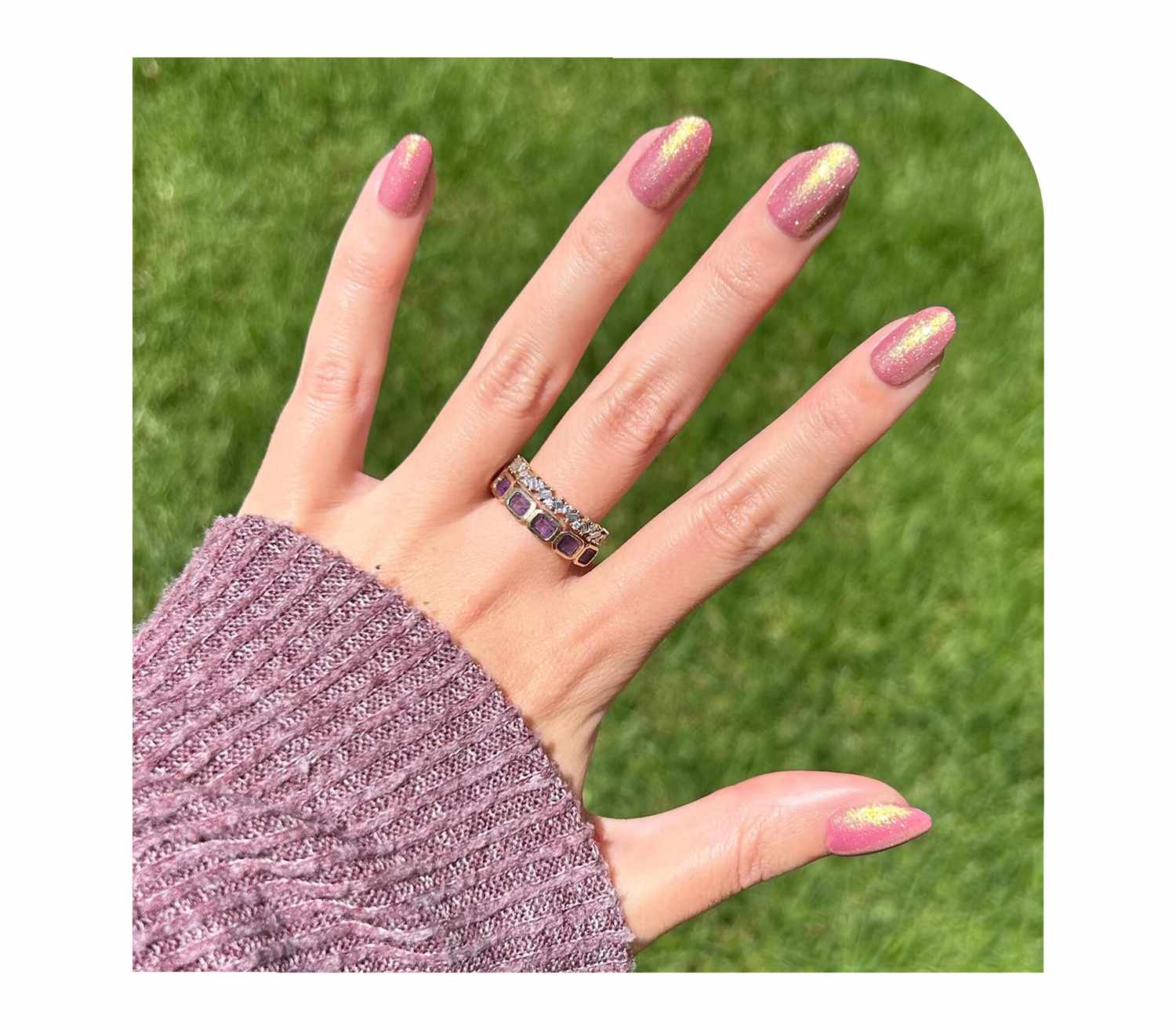 Model wearing a glittering pink manicure and purple sweater