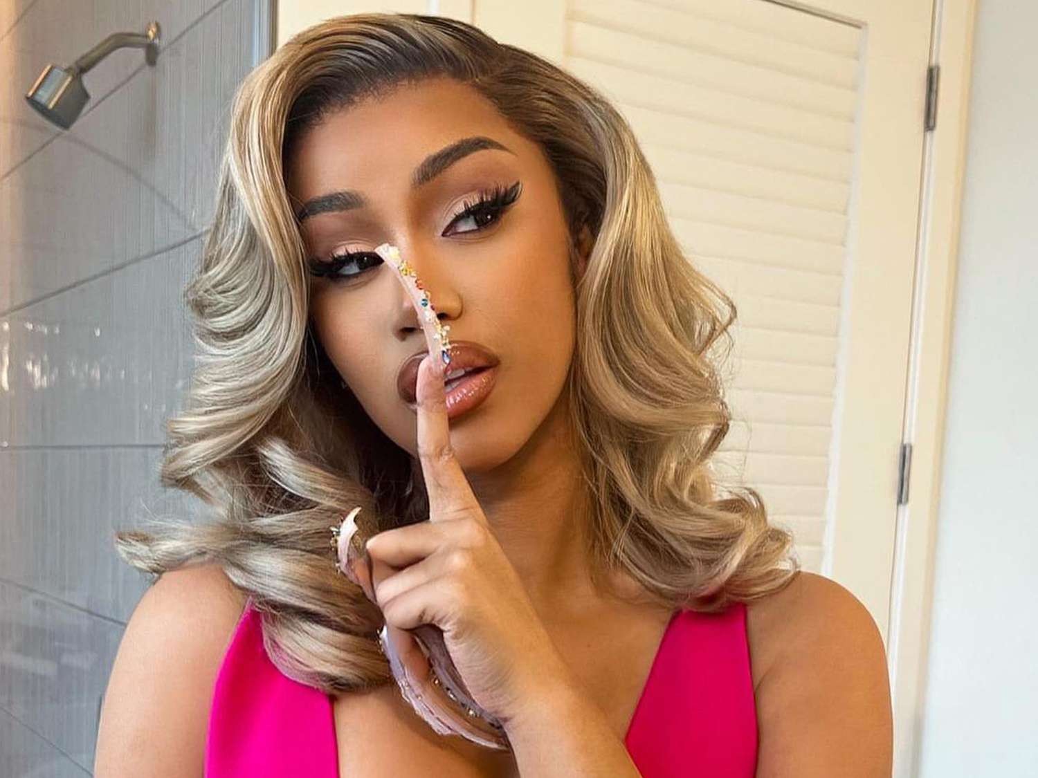 Cardi B with long nails, a pink top and blonde hair