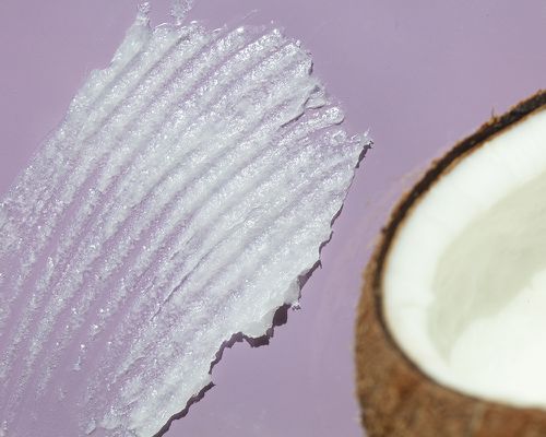 A swatch of coconut oil beside a coconut.