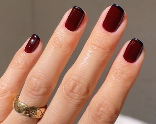 A short French manicure with a burgundy base and black tips