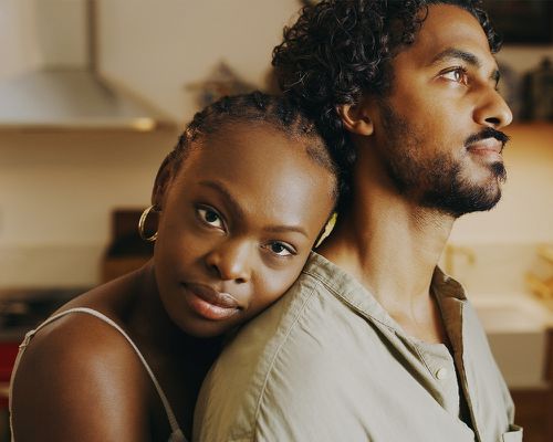 Shot of an young woman hugging her boyfriend while bonding with him at home