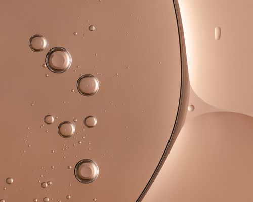 a skincare serum backlit with pink tone. bubbles and round shapes and highlights in the texture