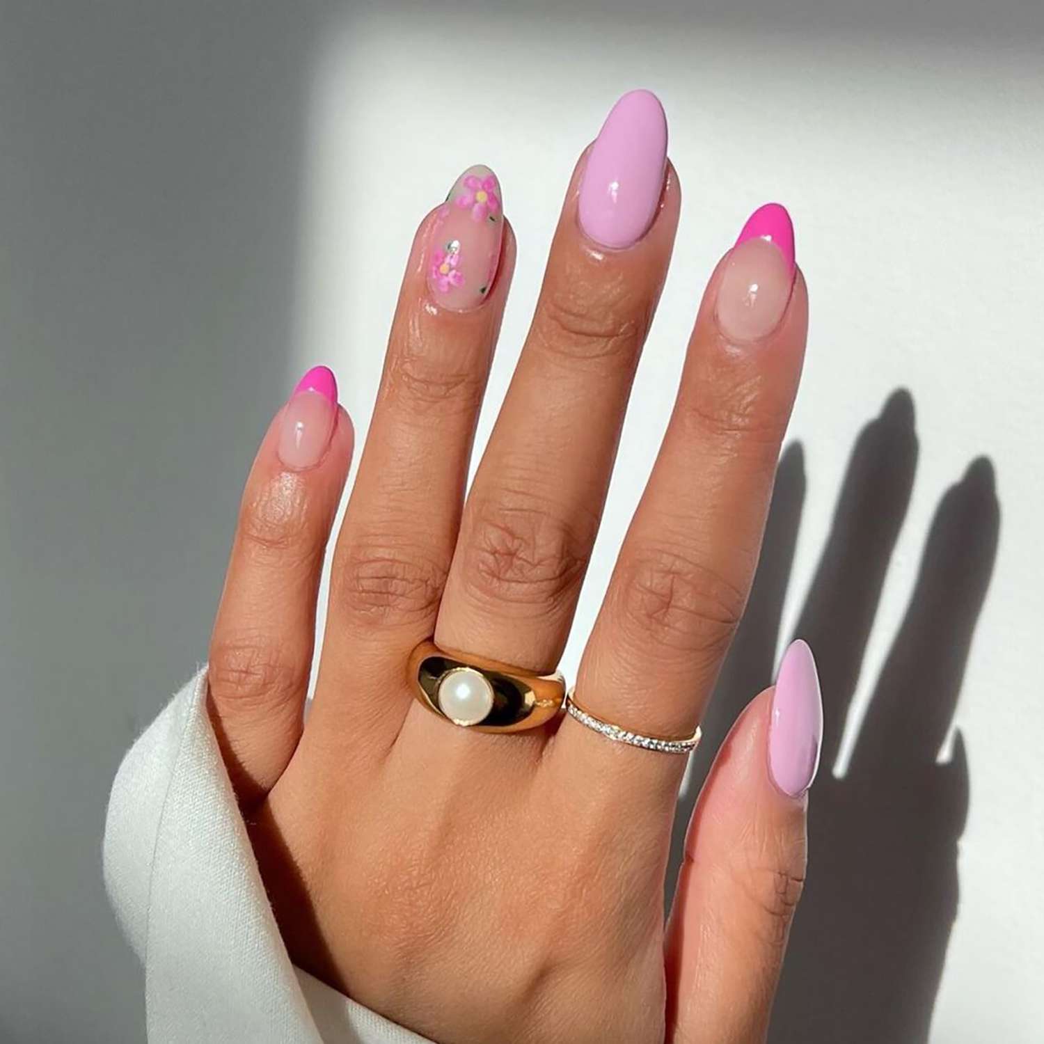 A baby pink manicure with floral and French tip accents