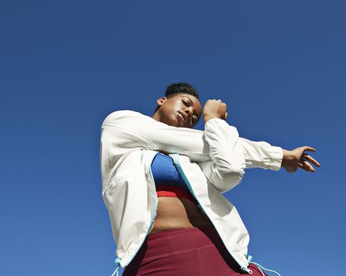 woman in white jacket stretching arms before a workout