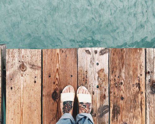 tattooed feet on dock overlooking water