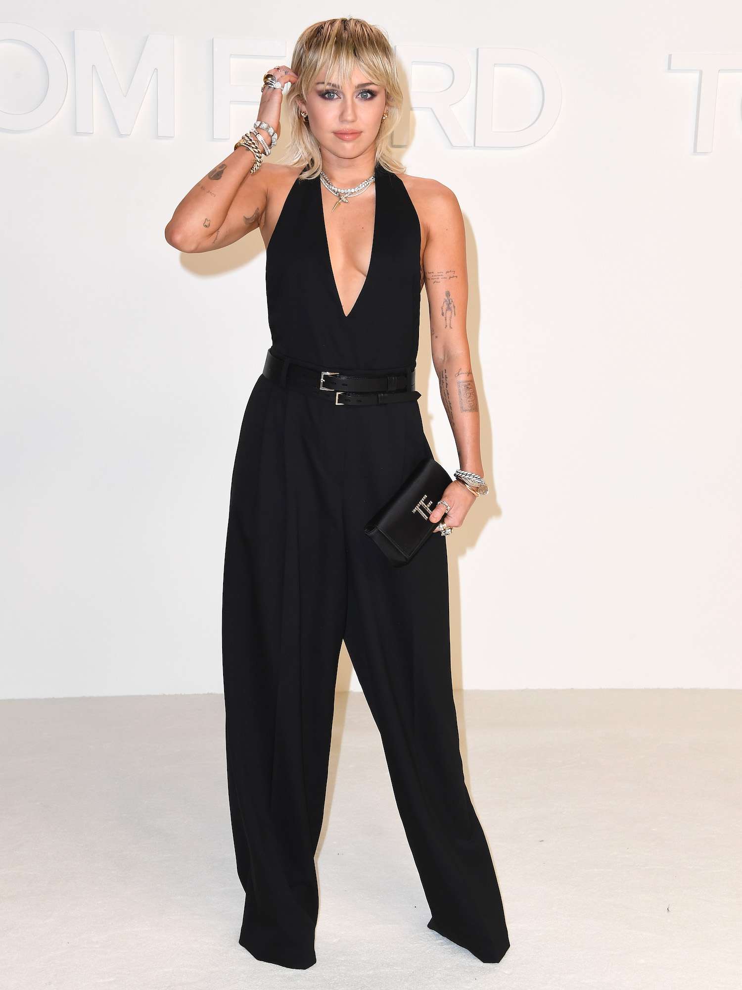 Miley Cyrus wears a black jumpsuit with plunging neckline to the Tom Ford Fall 2020 show