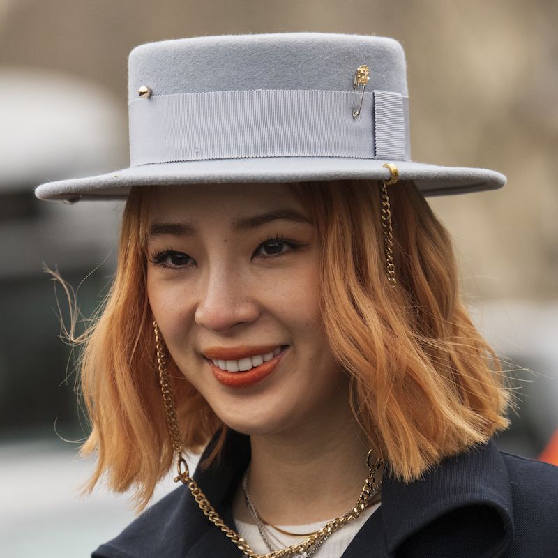 Irene Kim wears a light copper colored bob and gray brimmed hat