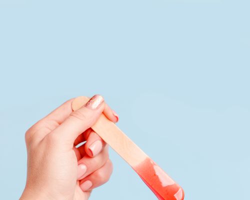 Hand holding wax on popsicle stick