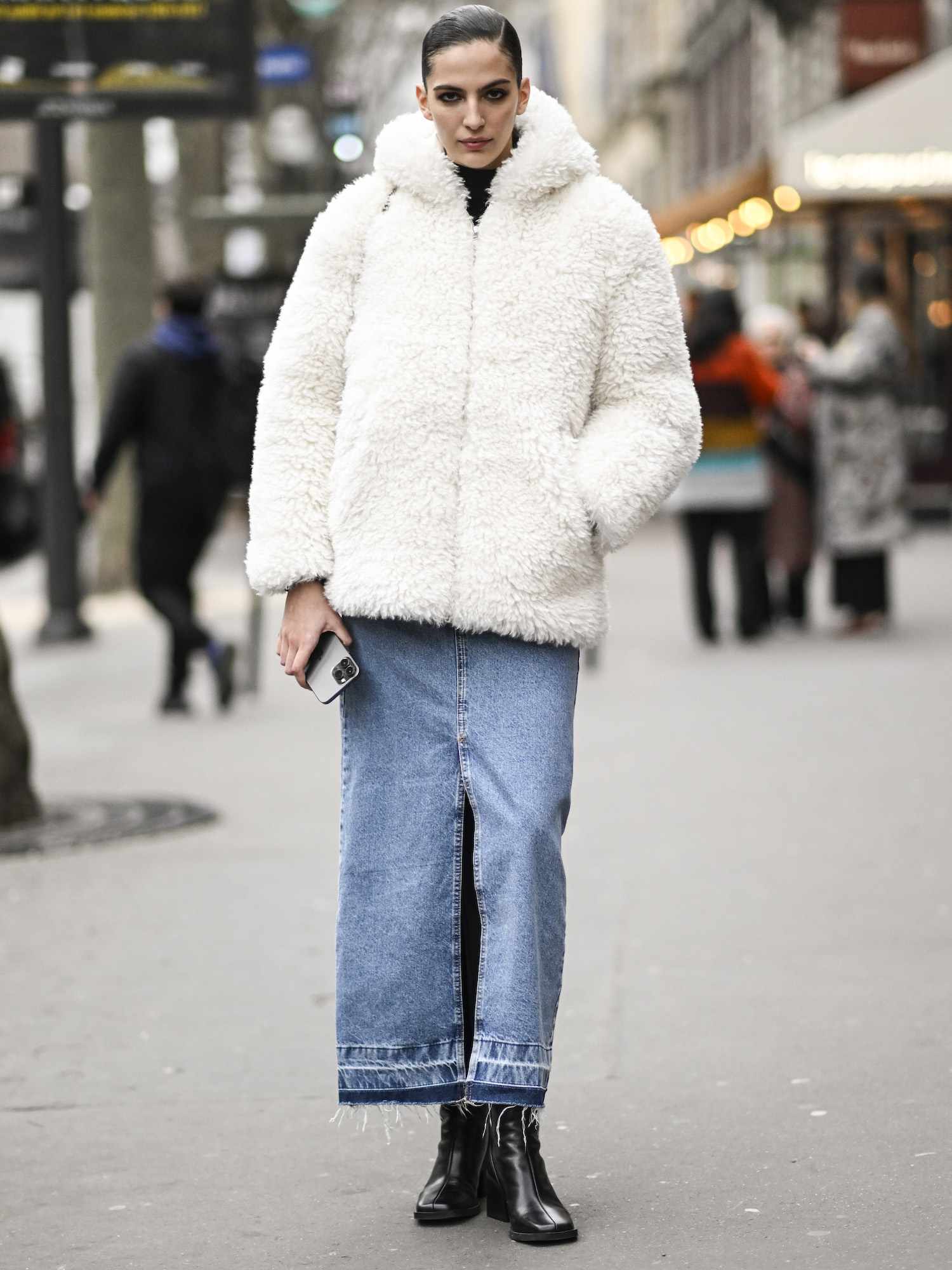 Africa Garcia wears a white fuzzy jacket, denim maxi skirt with slit, and black boots