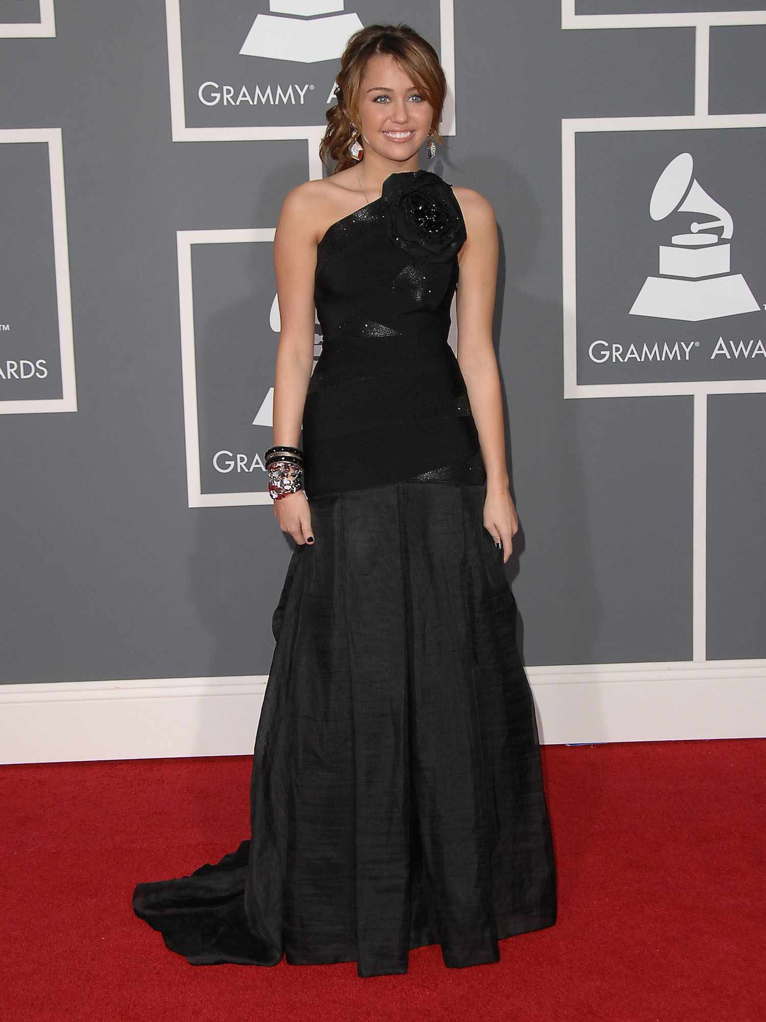 Miley Cyrus wears a black Herve Leger by Max Azria gown to the 2009 Grammy Awards