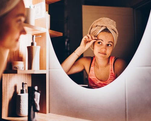 Young white woman plucking her eyebrows