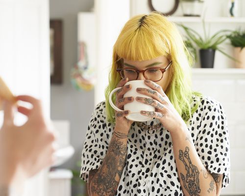 Young woman drinking coffee in her kitchen