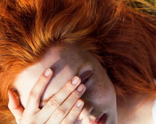 Red-headed woman with hand on face