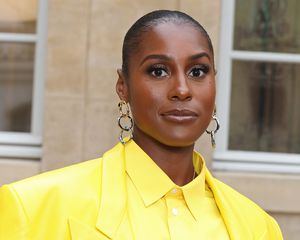 Issa Rae in an all yellow suit, dangling gold earrings, and a slicked back bun