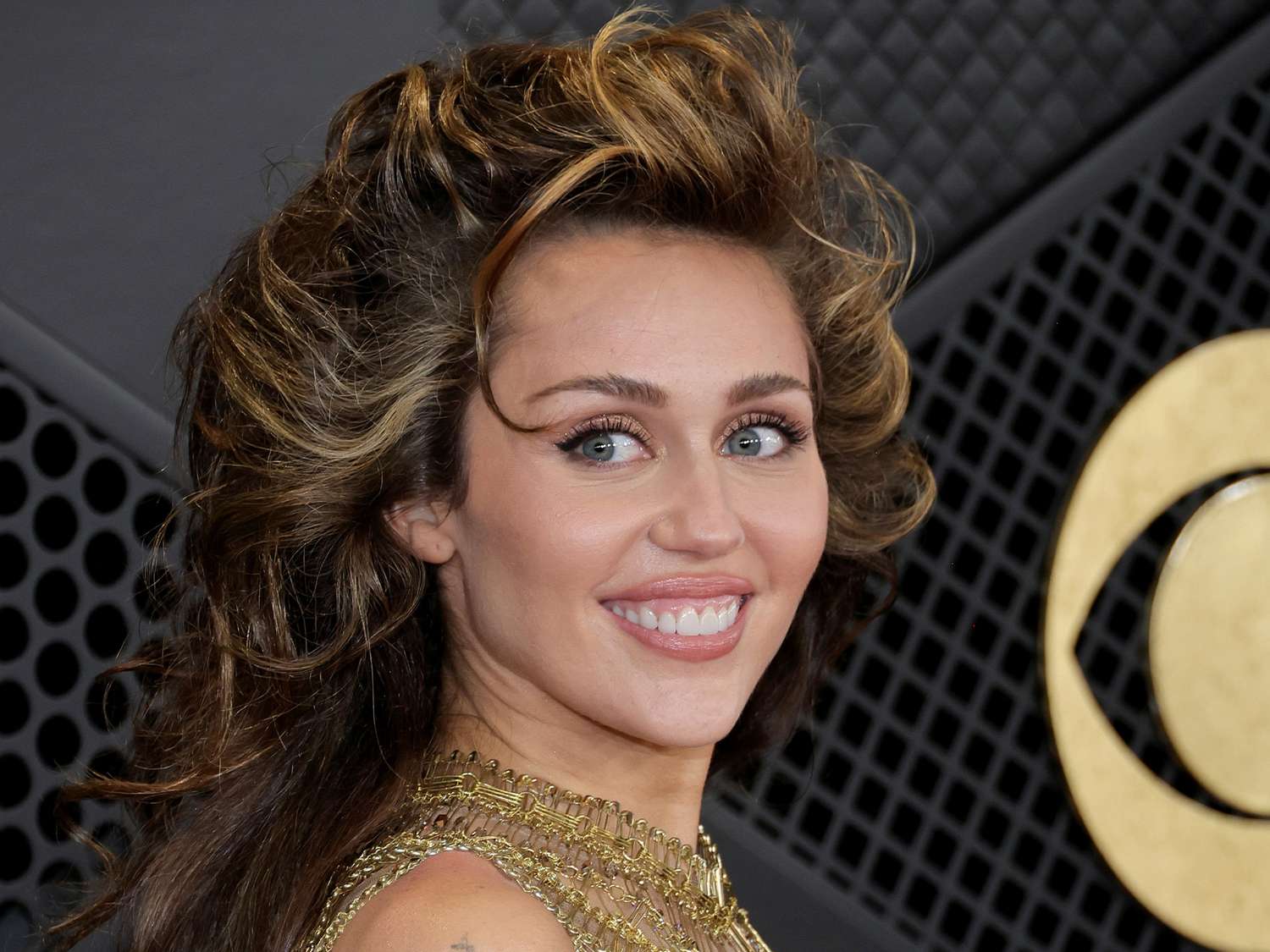 Miley Cyrus at the Grammys with a country star blowout hairstyle and a golden Maison margiela dress