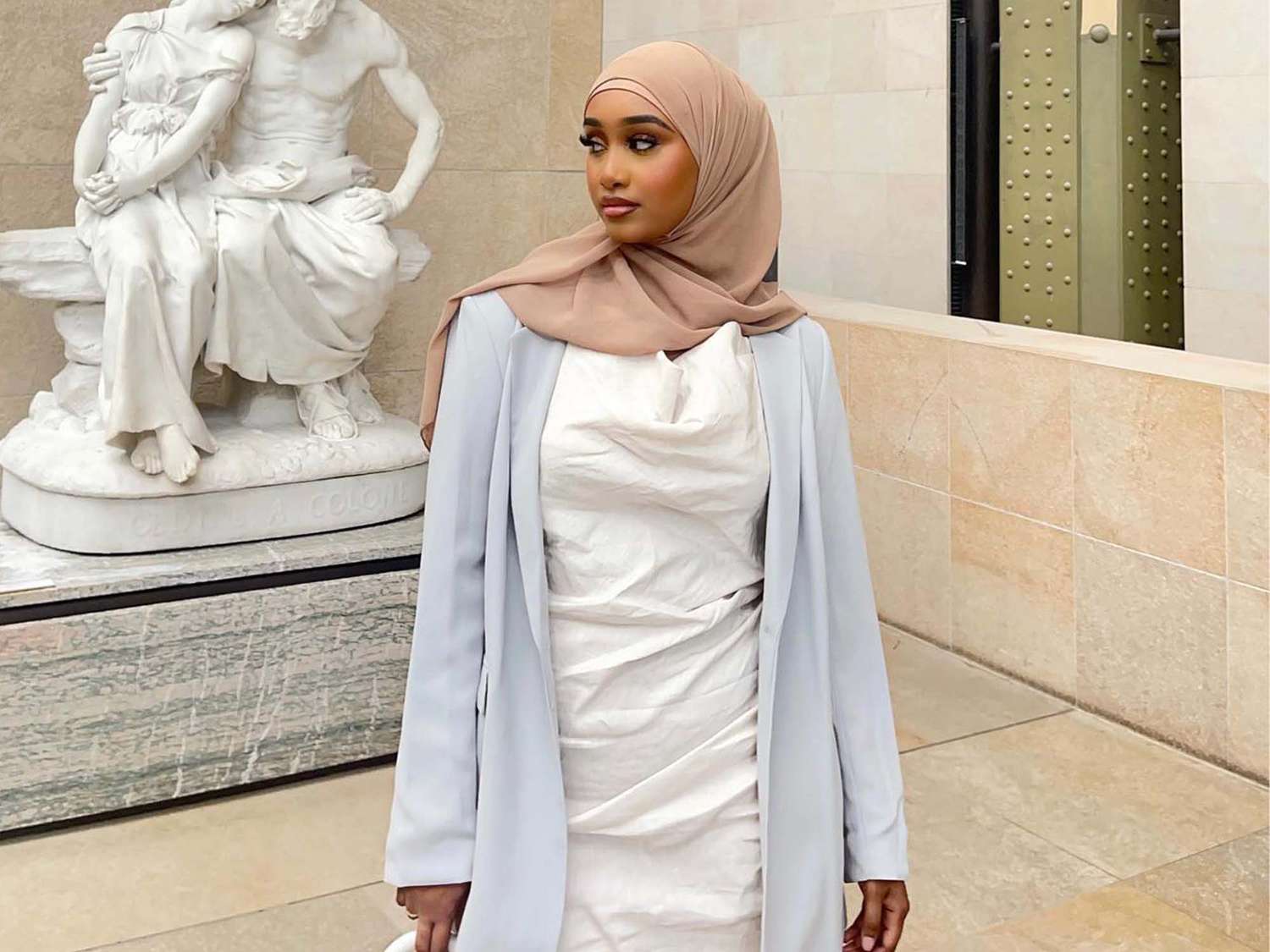 Luley Jeylani wearing a white dress and light blazer at a museum.