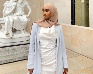 Luley Jeylani wearing a white dress, light blazer, and tan hijab at a museum in Paris.